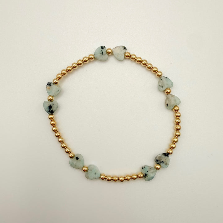 Bracelet with gold beads and greenstone beads on a light background