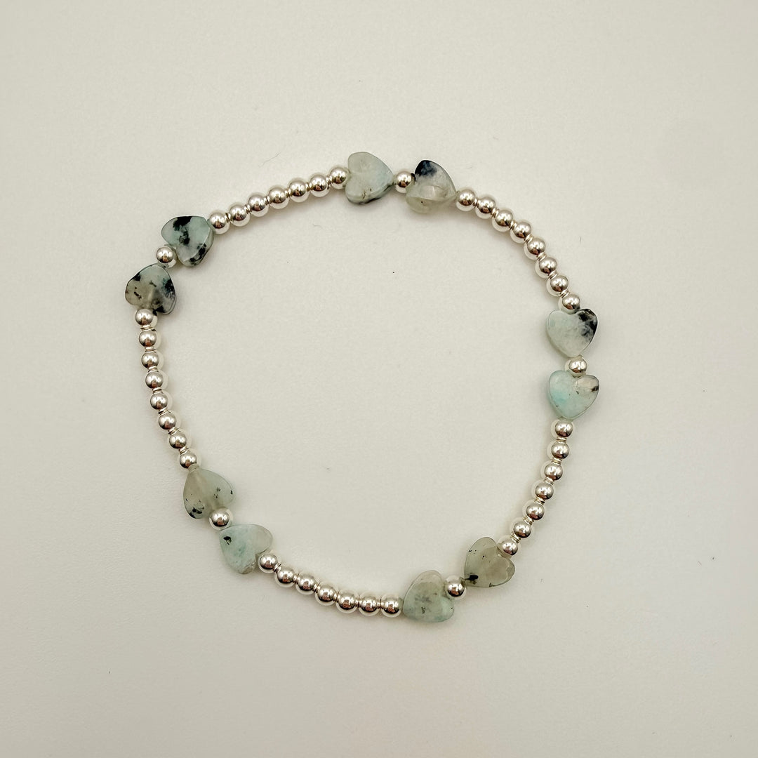 Bracelet with heart-shaped green stones on a white background