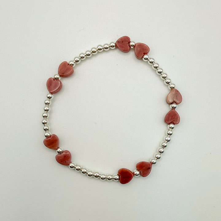 Bracelet with red heart-shaped beads and silver beads on a white background