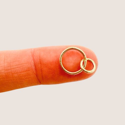 Gold ring on a finger against a beige background